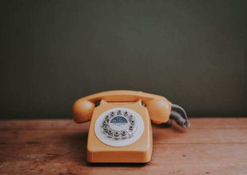 An old fashioned orange telephone used for sales cold calling