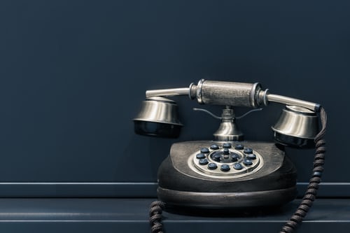 A 60's black telephone resting on a black window sill