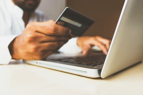 A person holding his card to make a transaction on his laptop