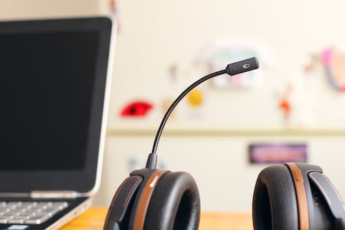 A salesperson's headphones and mic resting by a laptop after screen-sharing with a customer