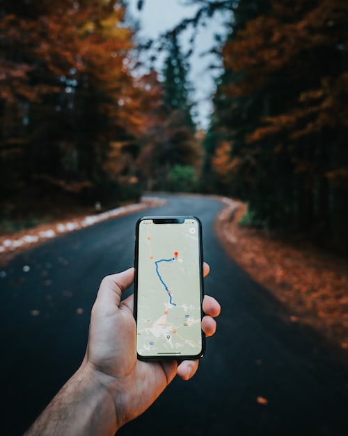 A person holding an iPhone with maps on in the countryside