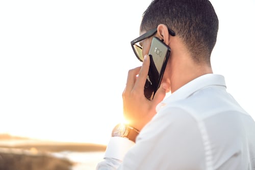 A telesales agent on a call wearing a white shirt outside